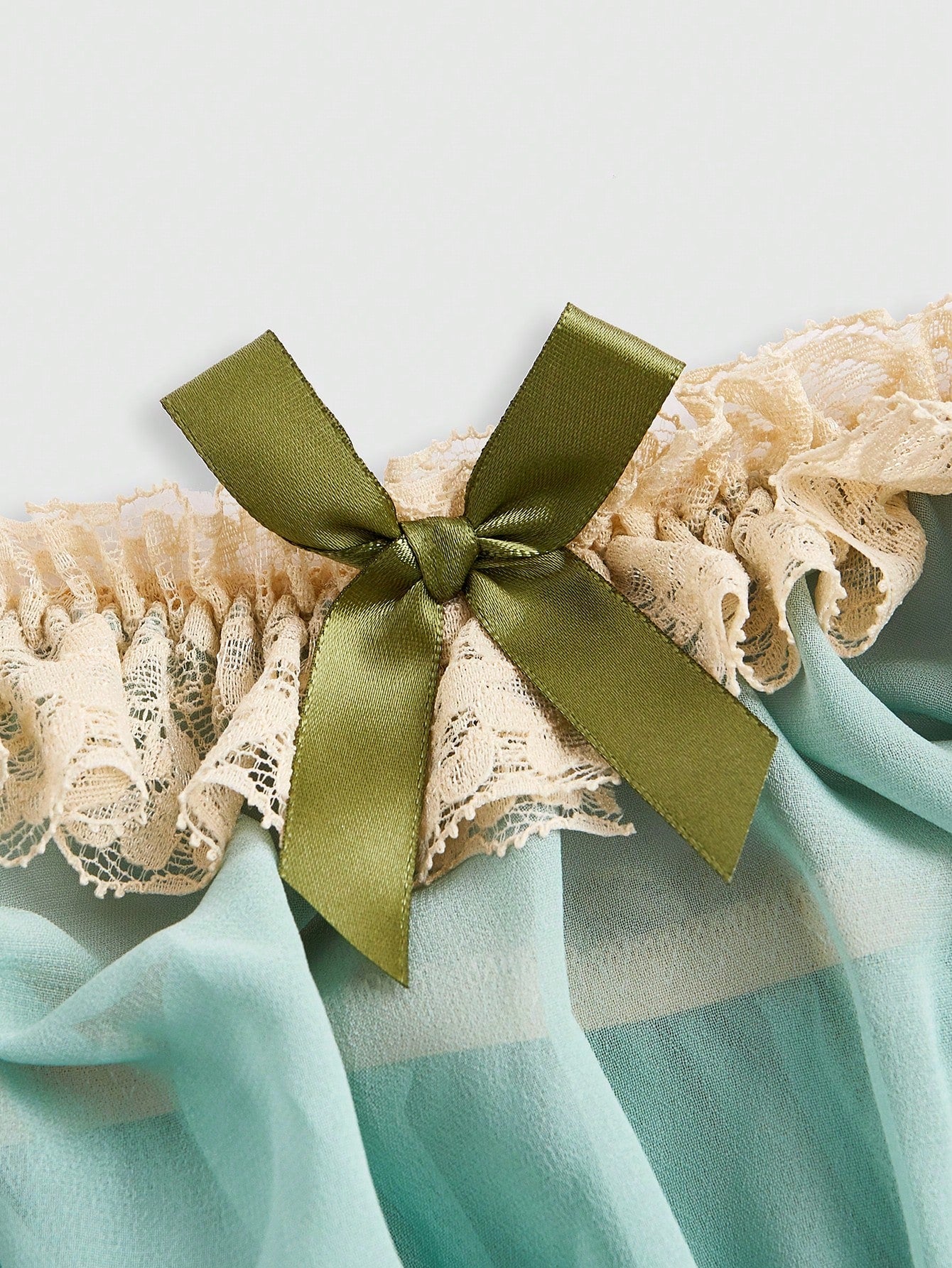 Close-up of loungewear top showing delicate lace and bowknot accents