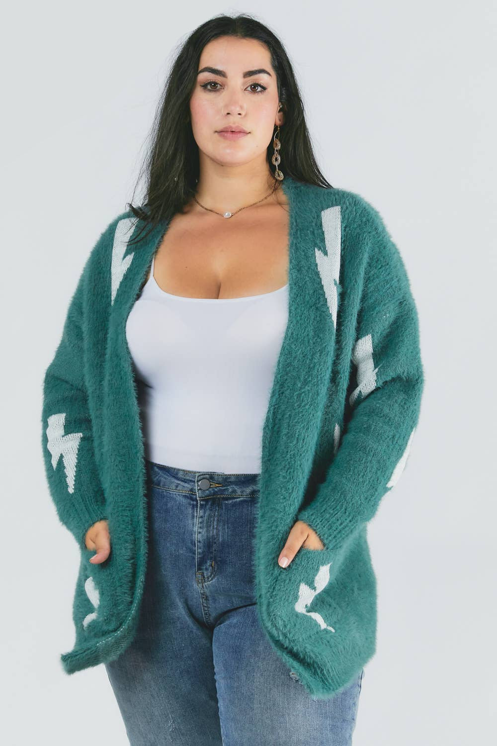 Woman wearing a green cardigan with white patterns on a plain background