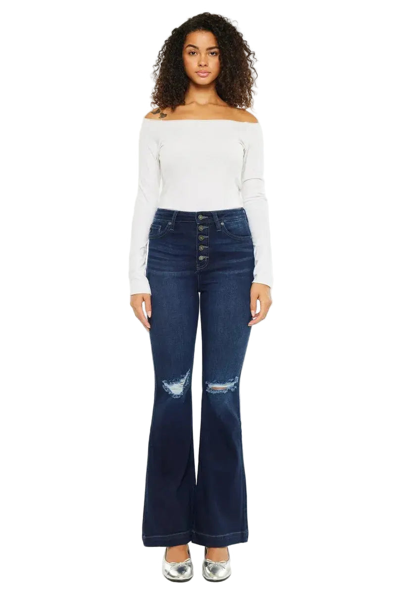 Woman wearing a white off-shoulder top and blue flared jeans on a white background