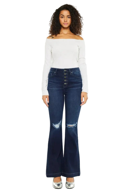 Woman wearing a white off-shoulder top and blue flared jeans on a white background