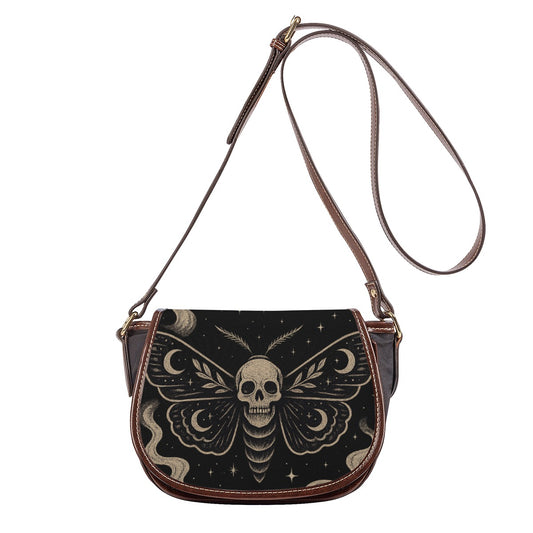 Front view of saddle crossbody bag with skull moth and moon design on black flap, adjustable strap. 