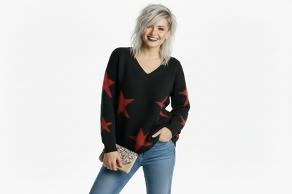 Woman wearing a black sweater with red star patterns and blue jeans on a white background